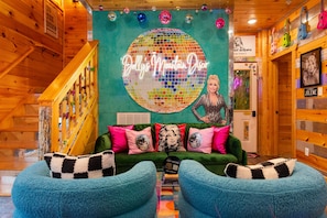A cozy room with a green couch, a disco ball, and wooden walls. - Heated Pool, Arcades, Hot Tub, Sauna, Dolly Vibes (Sevierville)