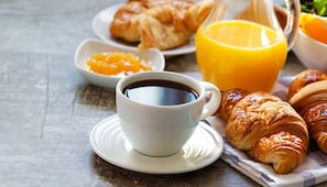 Un desayuno con croissants, jugo de naranja y café.