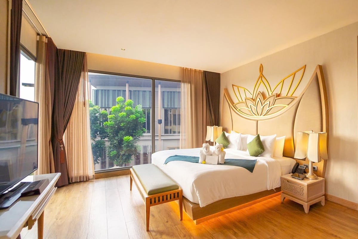 Una habitación de hotel con una cama grande, una mesita de noche y vistas al exterior.