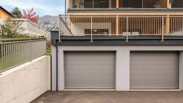 A two-story building with a balcony and a garage with closed doors.