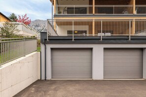 A two-story building with a balcony and a garage with closed doors. - Mountain Lodge Apartment (Gröbming)