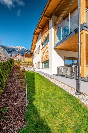 A modern building with a sloped roof, large windows, and a well-maintained lawn. - Mountain Lodge Apartment (Gröbming)
