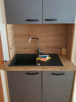 Eine Küche mit einem schwarzen Spülbecken, Holzschränken und einem Edelstahlarmaturenwerk.