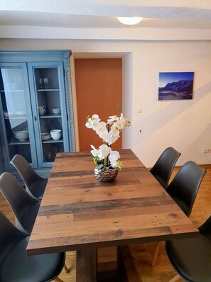Ein Esstisch mit Stühlen, eine Speisekammer mit Geschirr und eine Orchidee im Topf.