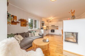 Een moderne woonkamer met een grijze bank, een ronde houten salontafel en een zacht, wit vloerkleed.