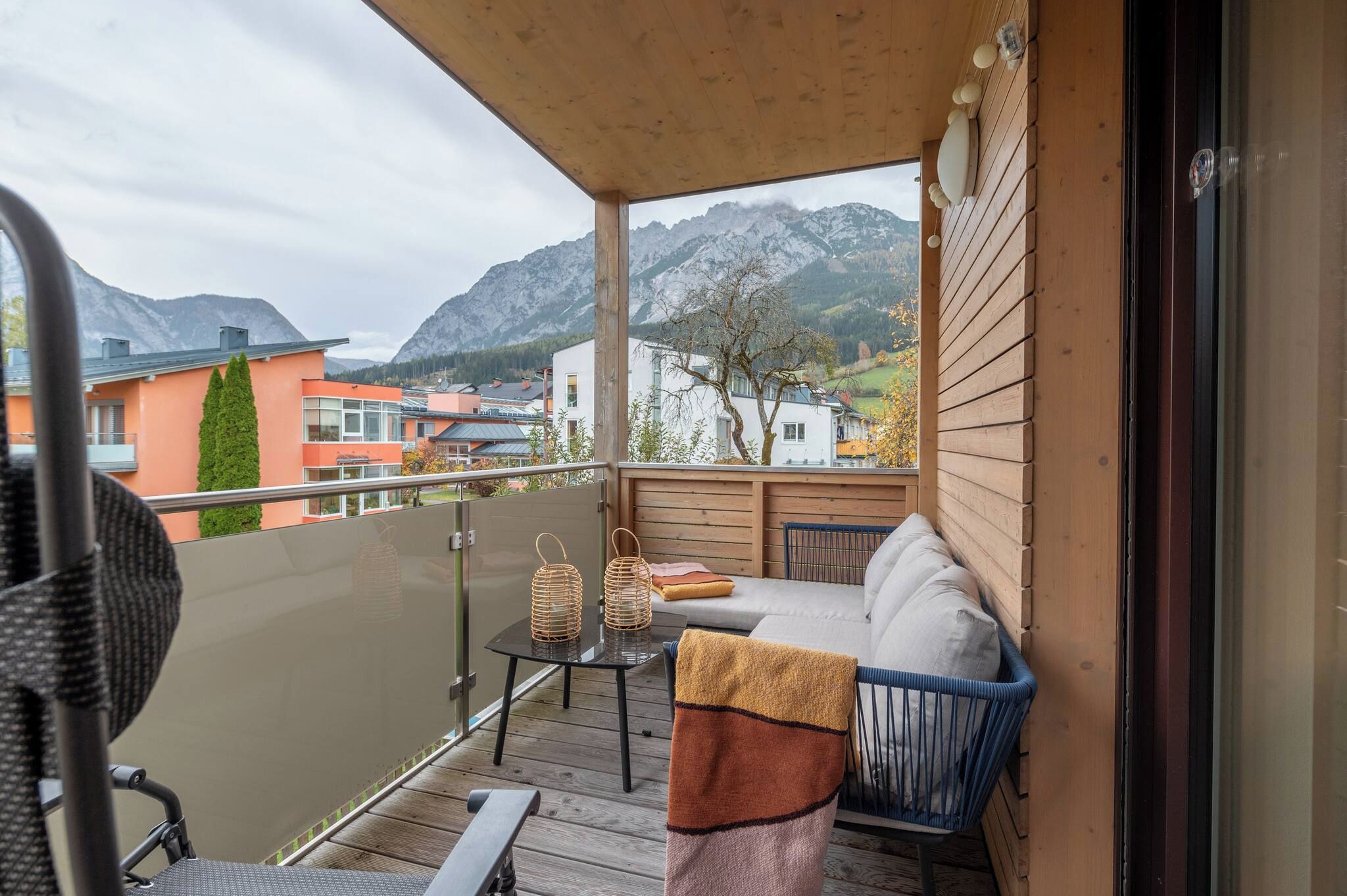 Ein Balkon mit Bergblick, ein Tisch mit zwei Laternen und ein Sofa mit Decke.
