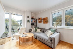 Een moderne woonkamer met een grijze bank, een houten salontafel en een boekenkast.