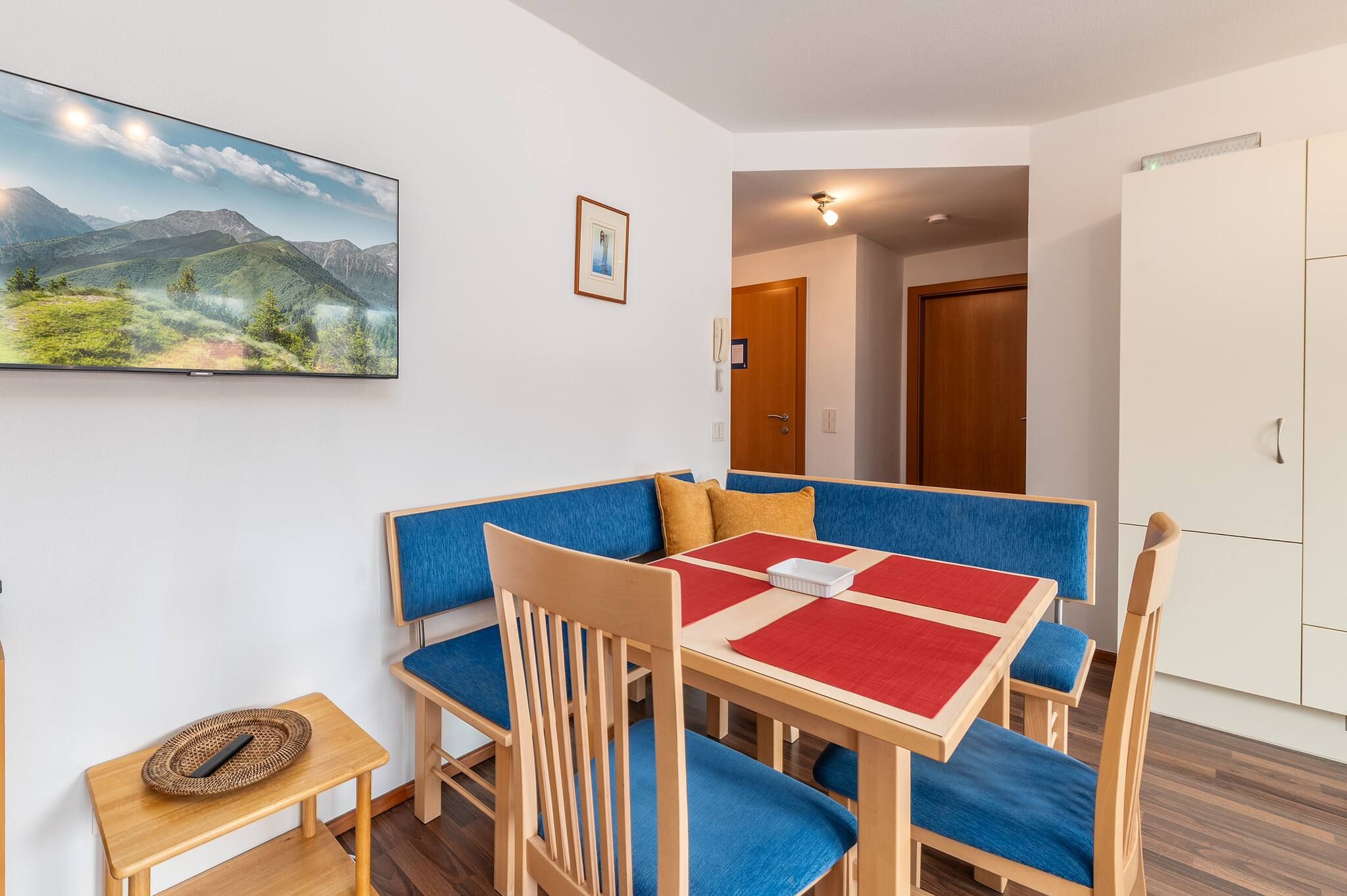 Une pièce comprenant une table à manger, des chaises à revêtement bleu, une petite table d’appoint et un tableau encadré accroché au mur.