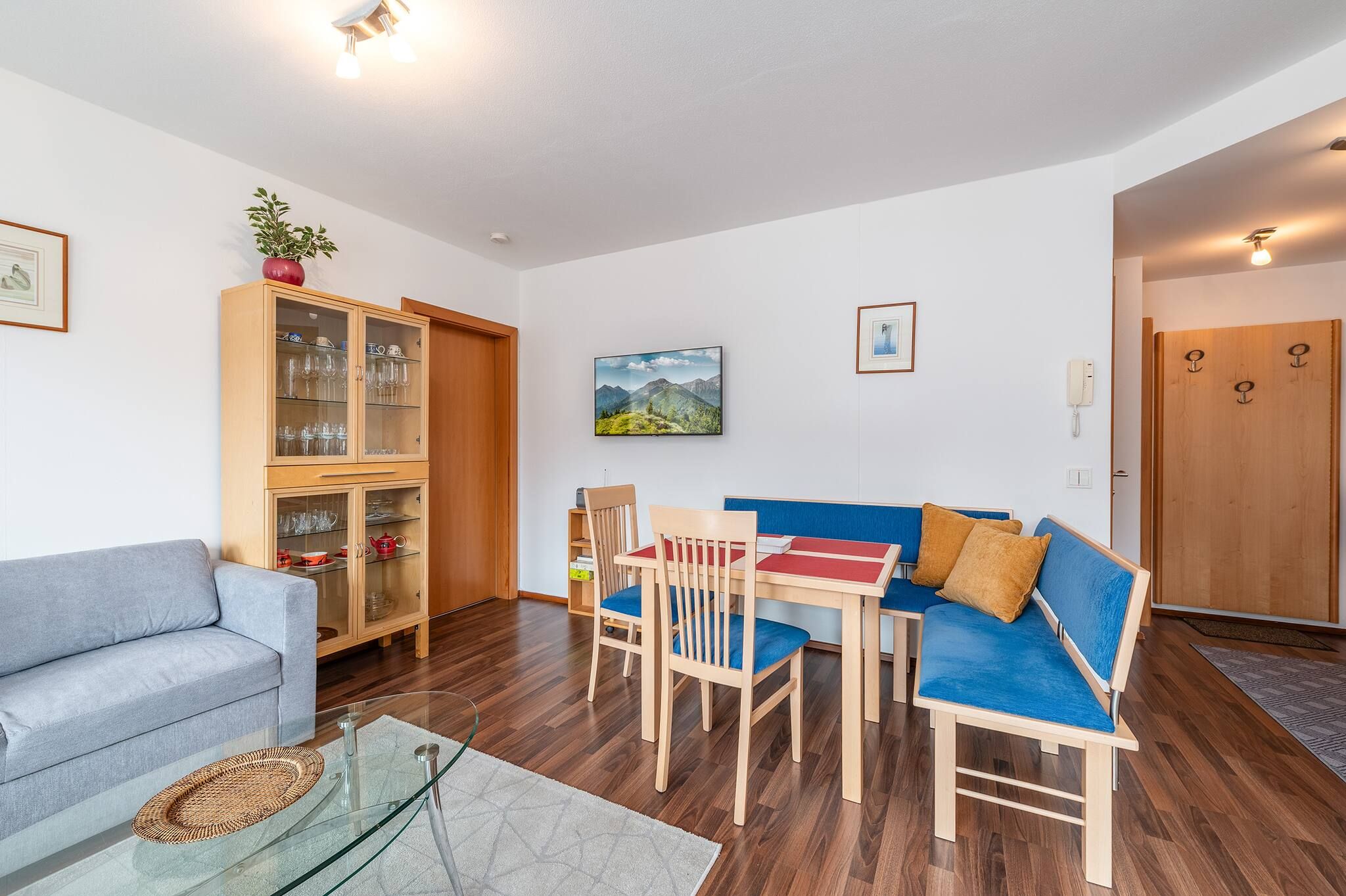 Un salon comprenant un canapé, des fauteuils, une table basse en verre et un meuble en bois doté de portes en verre.