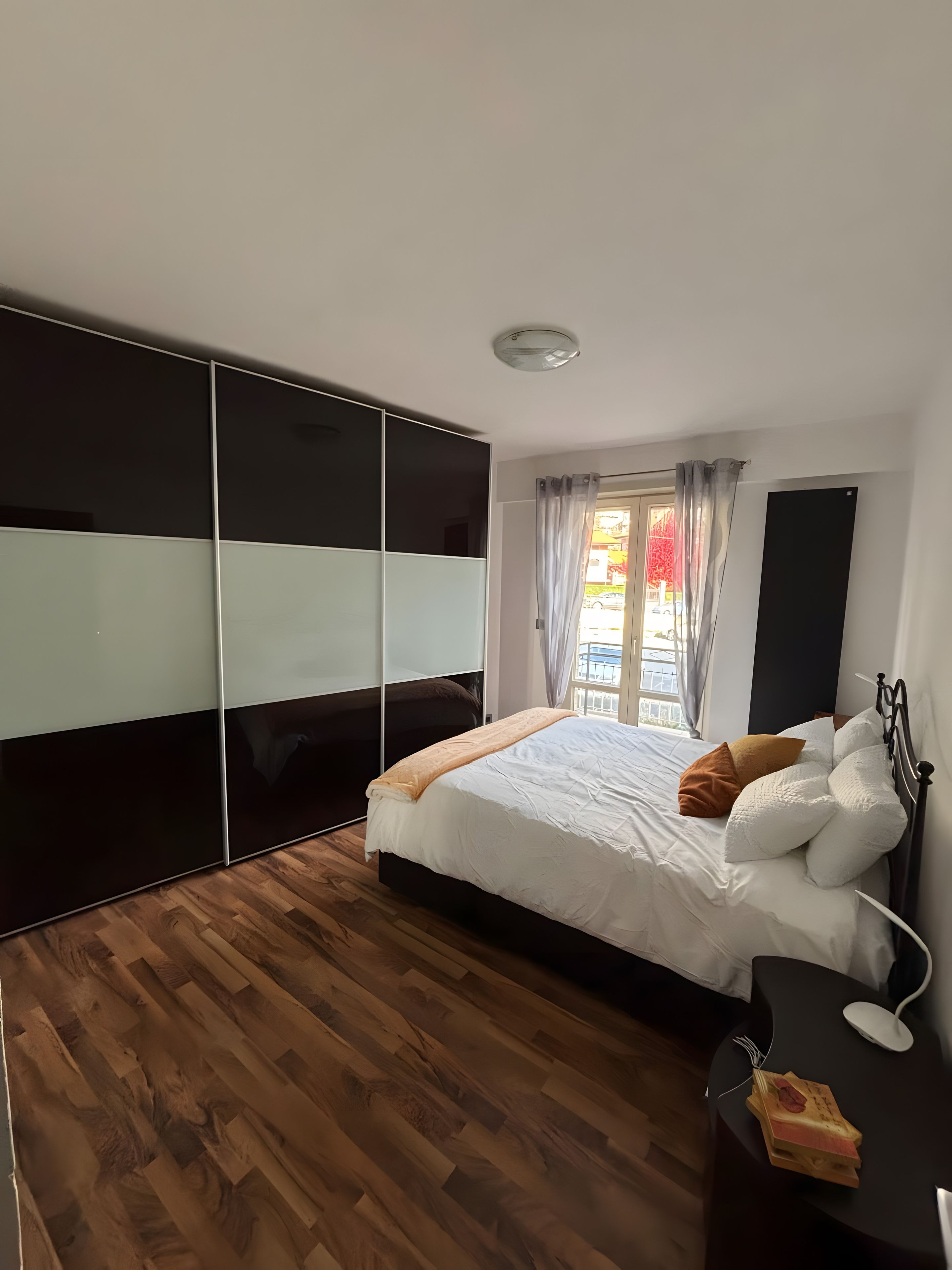 A bedroom with a bed, bedside table, and a wardrobe.