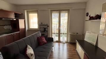 Um espaço de estar moderno com sofá, área de cozinha e mesa de jantar.