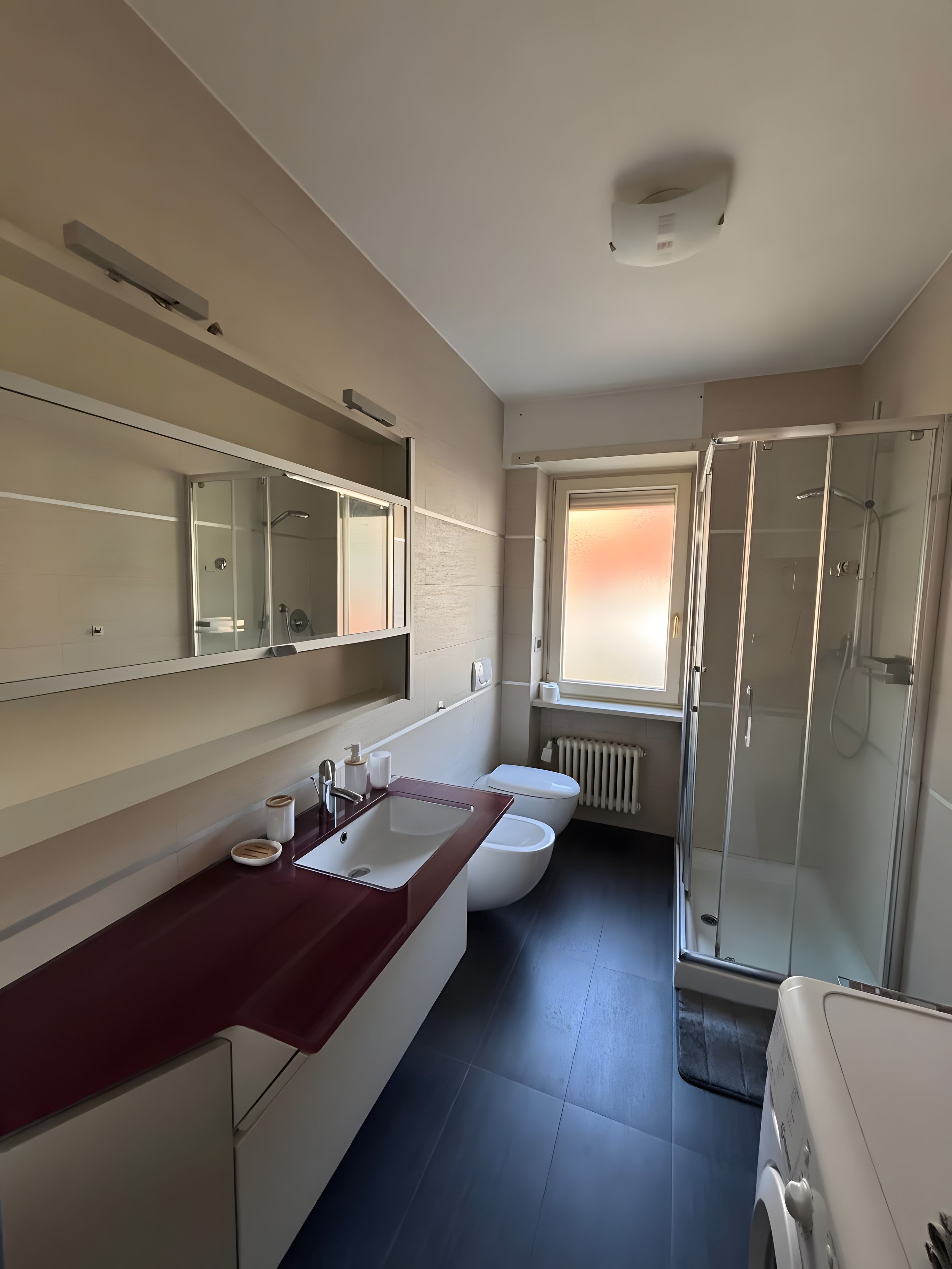 Ein modernes Badezimmer mit großem Spiegel, Waschbecken, Toilette und Duschbereich.