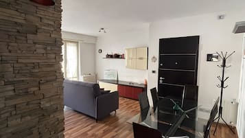A modern living space with a dining area, a kitchen, and a stone accent wall.