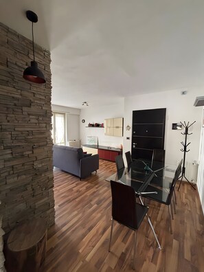 Un espacio moderno para vivir con comedor, cocina y una pared de acento de piedra.
