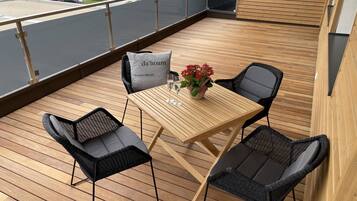 Eine Holzterrasse mit Tisch und Stühlen, einer Blumenvase und einem Kissen mit Schrift.