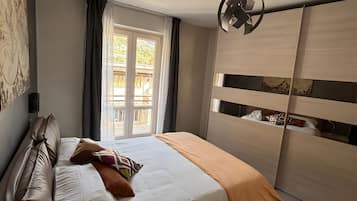 A bedroom with a bed, a bedside table, a wardrobe, a window, and a ceiling fan.