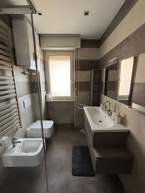 Et moderne badeværelse med badekar, en stor vask og en bruseniche.
