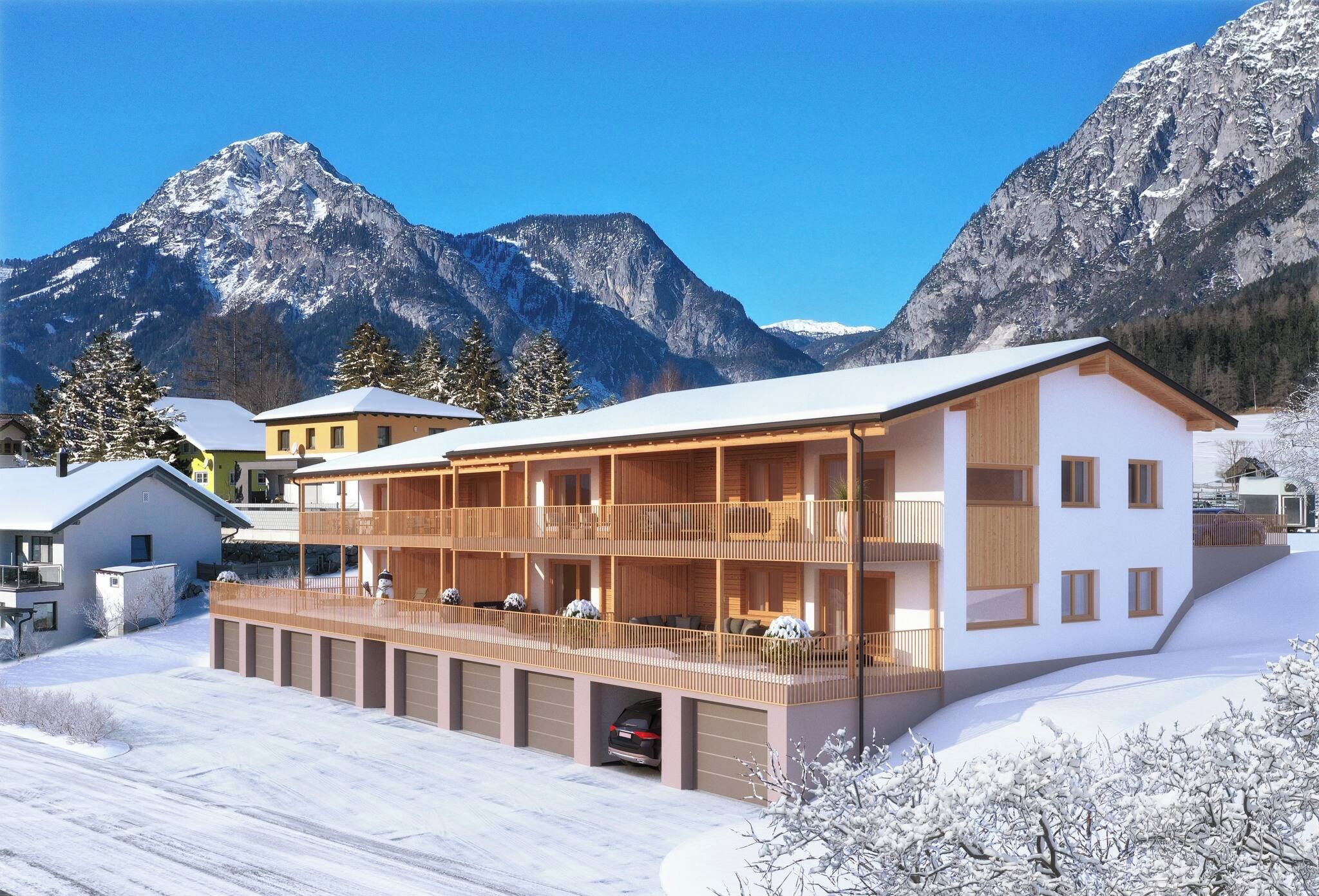 Ein modernes, zweistöckiges Gebäude mit einem Balkon, umgeben von verschneiter Landschaft und Bergen.