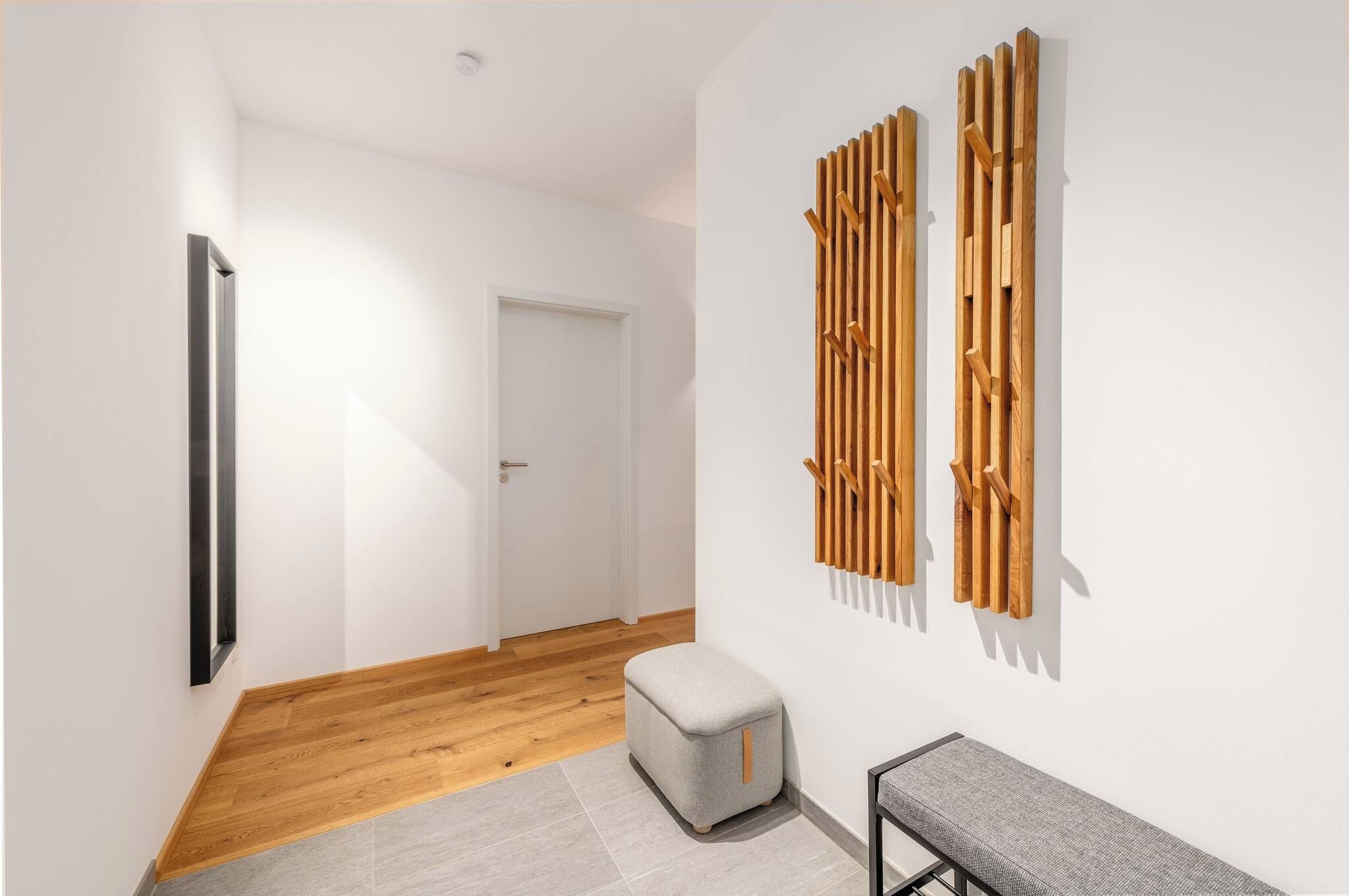 Ein Flur mit Holzboden, einer weißen Tür, einer Bank und einer an der Wand befestigten Holzkonstruktion.