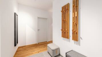 Ein Flur mit Holzboden, einer weißen Tür, einer Bank und einer an der Wand befestigten Holzkonstruktion.