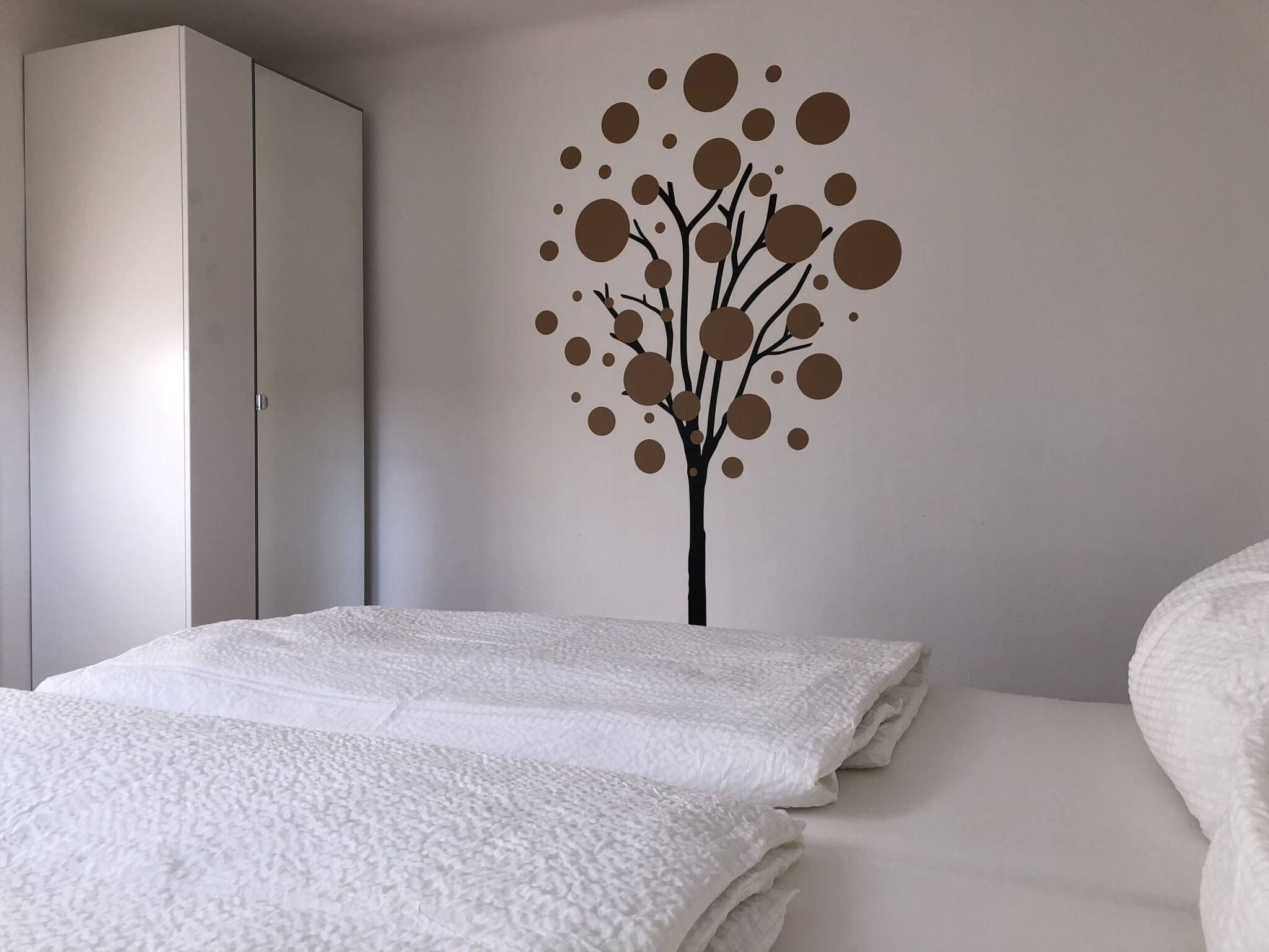 A bedroom with a bed, a wardrobe, and a wall decoration.