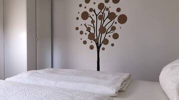 A bedroom with a bed, a wardrobe, and a wall decoration.