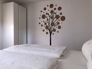 A bedroom with a bed, a wardrobe, and a wall decoration. - Apartment zur Schmiede (Gröbming)
