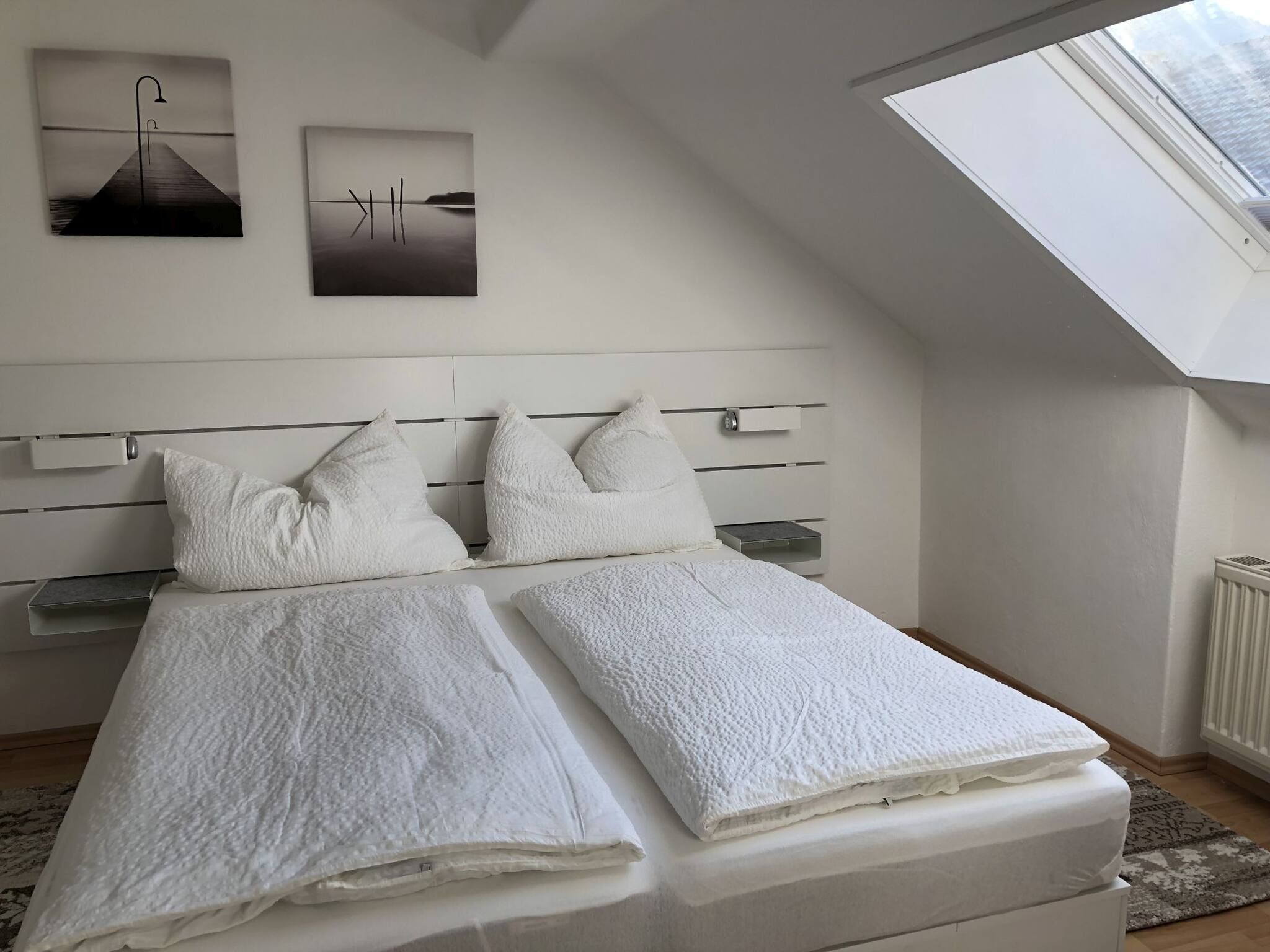 Ein Schlafzimmer mit einem Bett, zwei Kissen, einem Kopfteil und einem Oberlicht.
