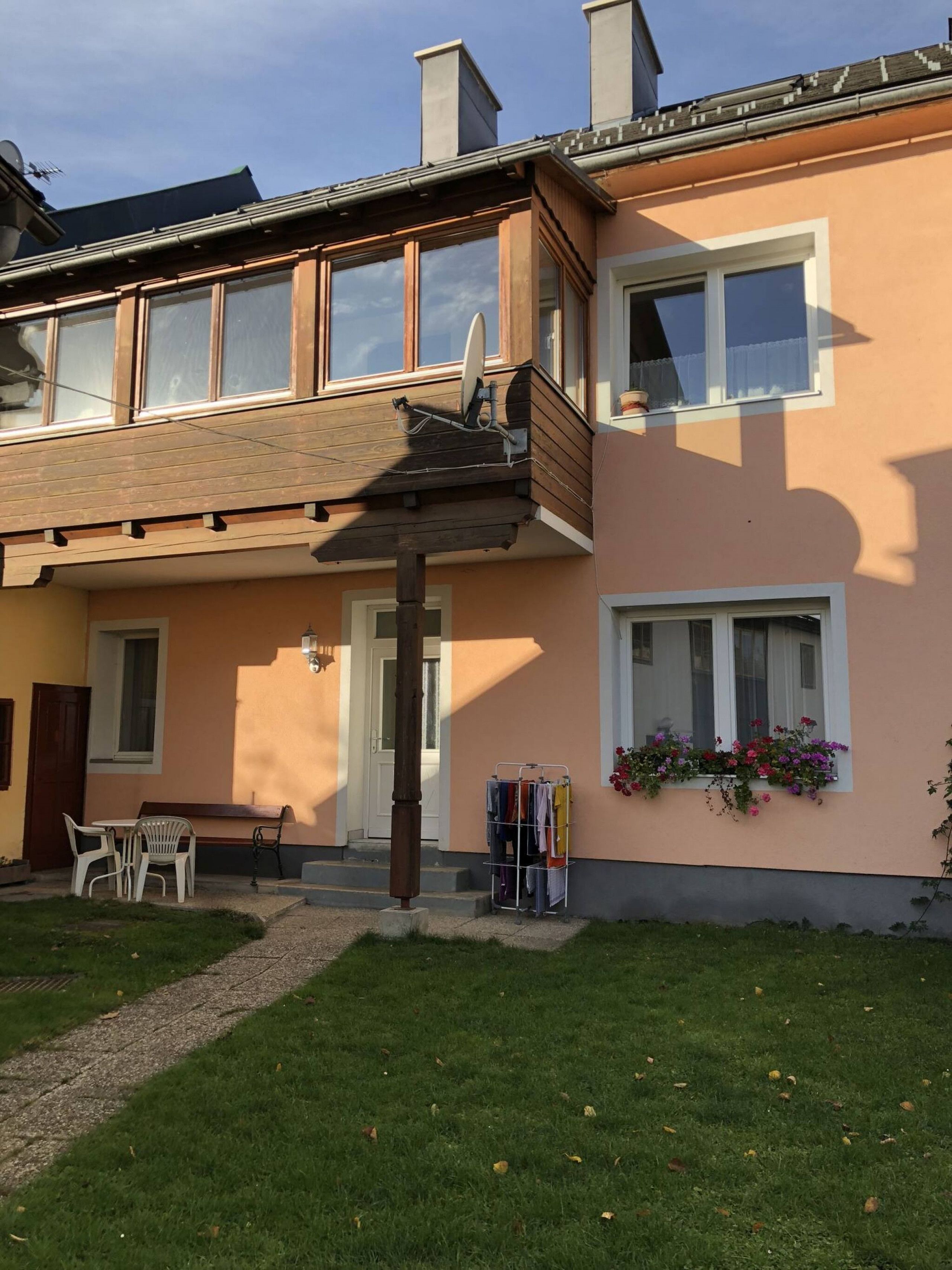 Ein zweistöckiges Gebäude mit einem Balkon, einer kleinen Außen-Sitzgelegenheit und einem Kleiderständer.
