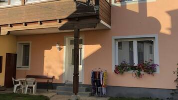 Ein zweistöckiges Gebäude mit einem Balkon, einer kleinen Außen-Sitzgelegenheit und einem Kleiderständer.