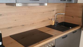 Eine moderne Küche mit grauen Schränken, einer Holzarbeitsplatte, einem eingebauten Backofen und einer Edelstahl-Dunstabzugshaube.