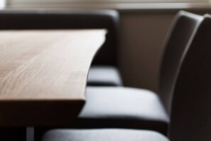 A close-up of a wooden table and a black cushioned chair. - Gästehaus Erika - Berg&Wald (Haus im Ennstal)