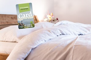 Ein Bett mit weißer Bettwäsche und einer Karte darauf.