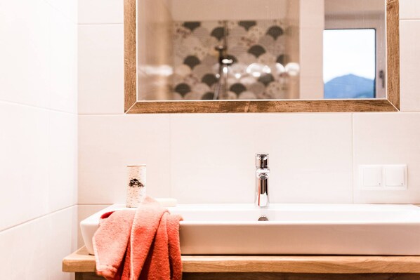 Un baño con lavamanos blanco, un espejo y una toalla.