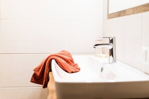 Ein Badezimmer mit einem weißen Waschbecken, einem Handtuch und einer Seifenspender.