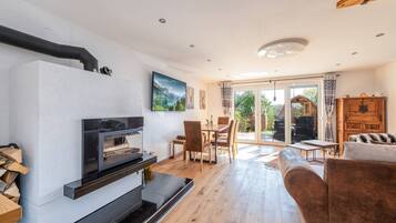 A modern living room with a fireplace, wooden flooring, and a view of the outdoors.
