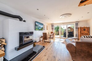 Un salon moderne avec une cheminée, un plancher en bois et une vue sur l’extérieur.