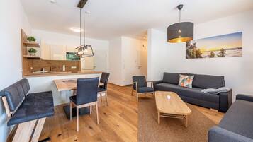 Ein moderner Wohnraum mit Essbereich, Sofa und einem Gemälde einer Berglandschaft.