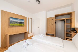 A hotel room with a bed, a wardrobe, a television, and a door. - Mountain Feelings Apartment (Gröbming)