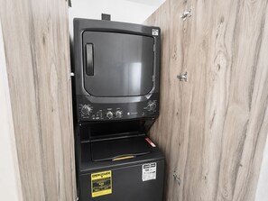 Una macchina distributrice nera con display digitale, addossata a un muro di legno.
