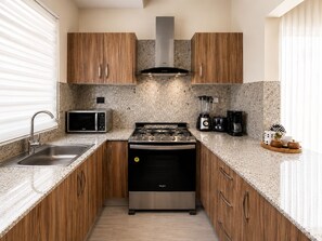 Una cucina moderna con mobili in legno, un fornello in acciaio inossidabile, un forno a microonde e una macchina da caffè.