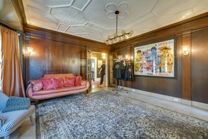 Ein Zimmer mit Teppichmuster, einem rosa Sofa, Holzvertäfelung und einem Poster an der Wand.