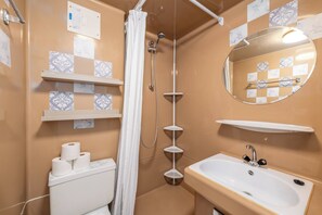 A bathroom with a toilet, a sink, a shower, and a mirror.