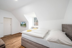 A bedroom with a sloped ceiling, a bed, a window, and a wall-mounted TV. - EasyStay Apartment Top 9 (Liezen)