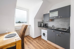 A compact kitchen with a built-in washer, a coffee maker, and a sink.