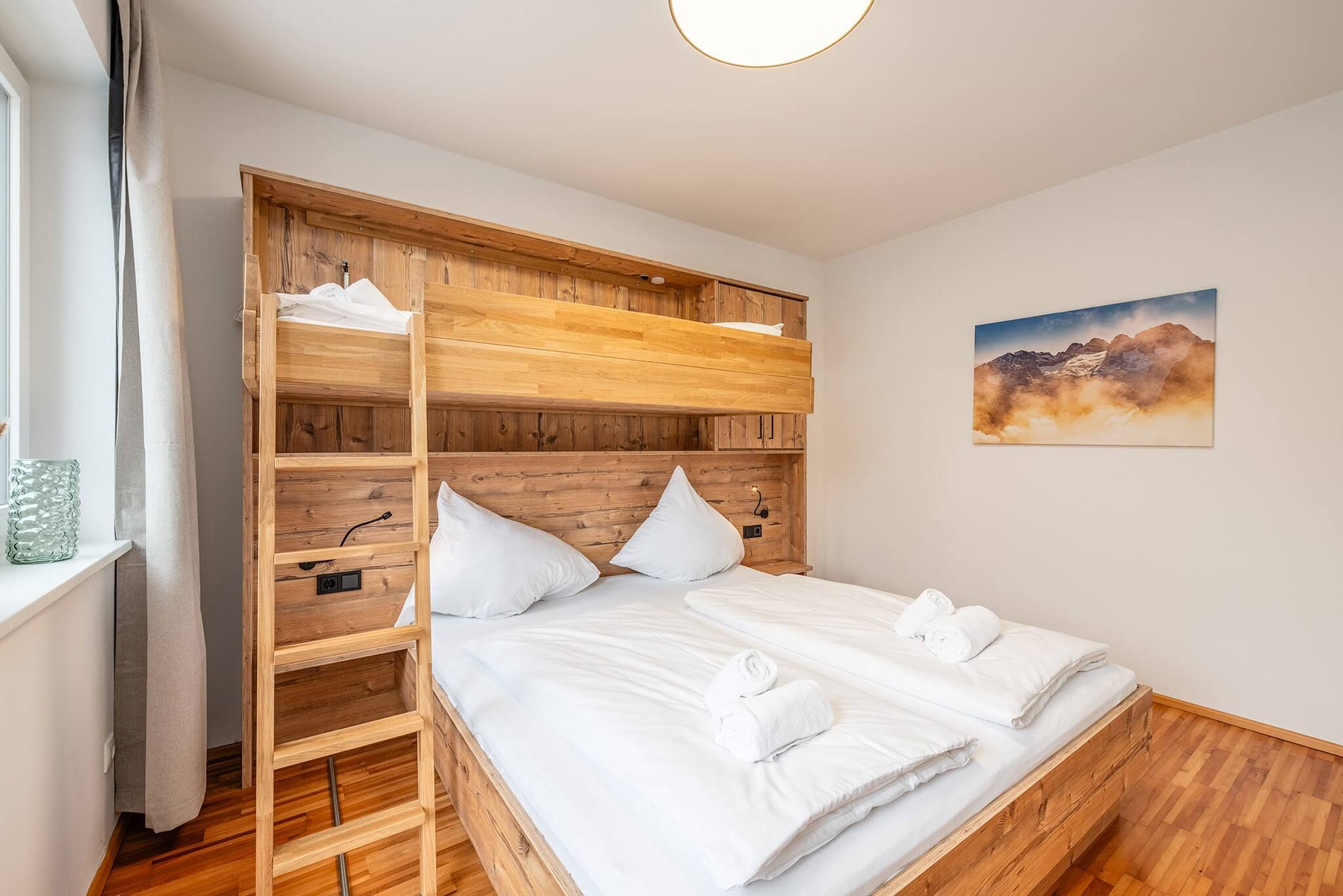 Un lit double avec du linge de lit blanc, une tête de lit en bois et un tableau accroché au mur.