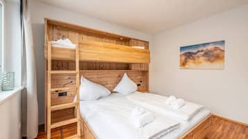 Un lit double avec du linge de lit blanc, une tête de lit en bois et un tableau accroché au mur.
