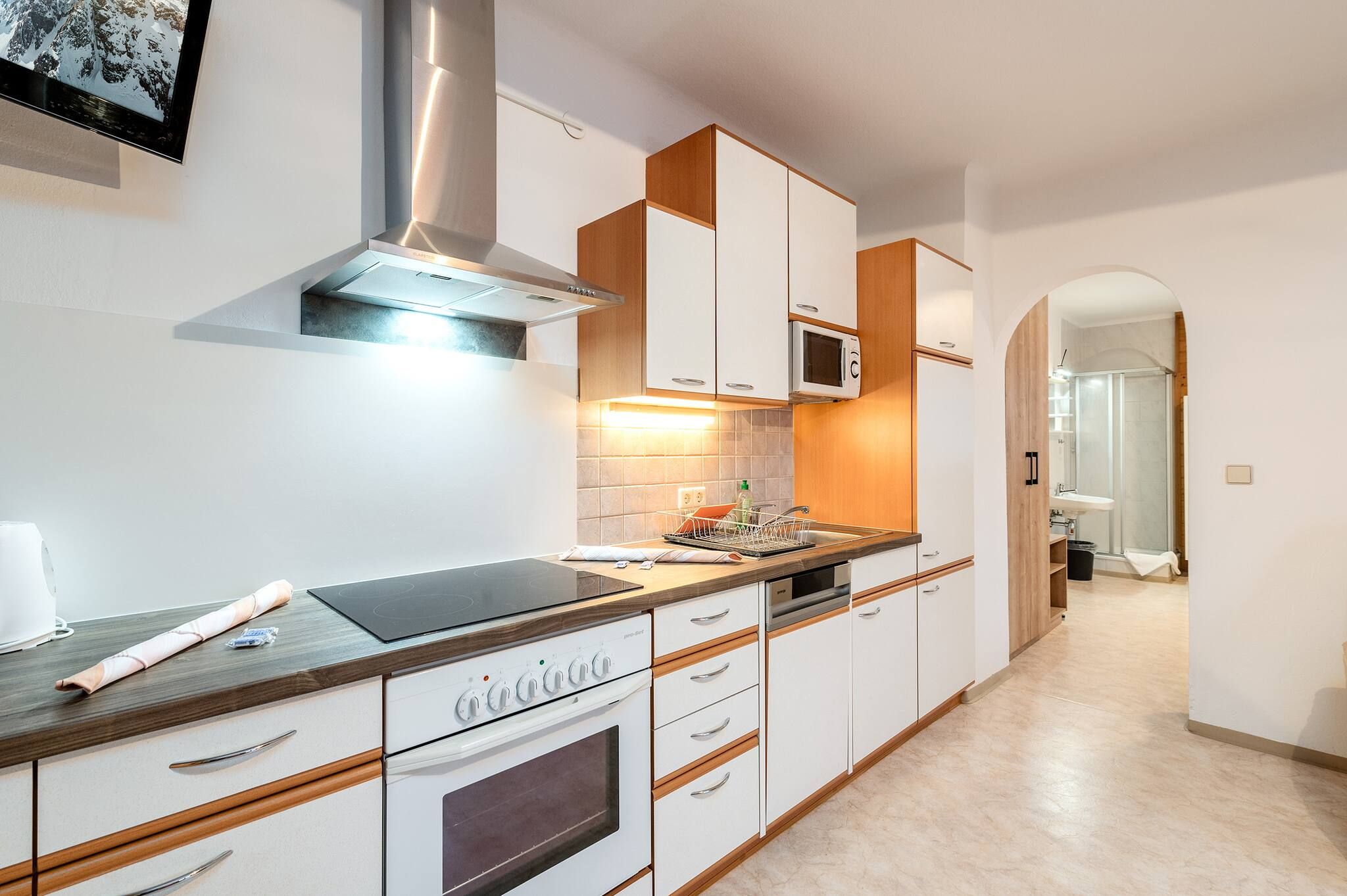 Een moderne keuken met witte kastjes, roestvrijstalen apparatuur en een houten aanrecht.