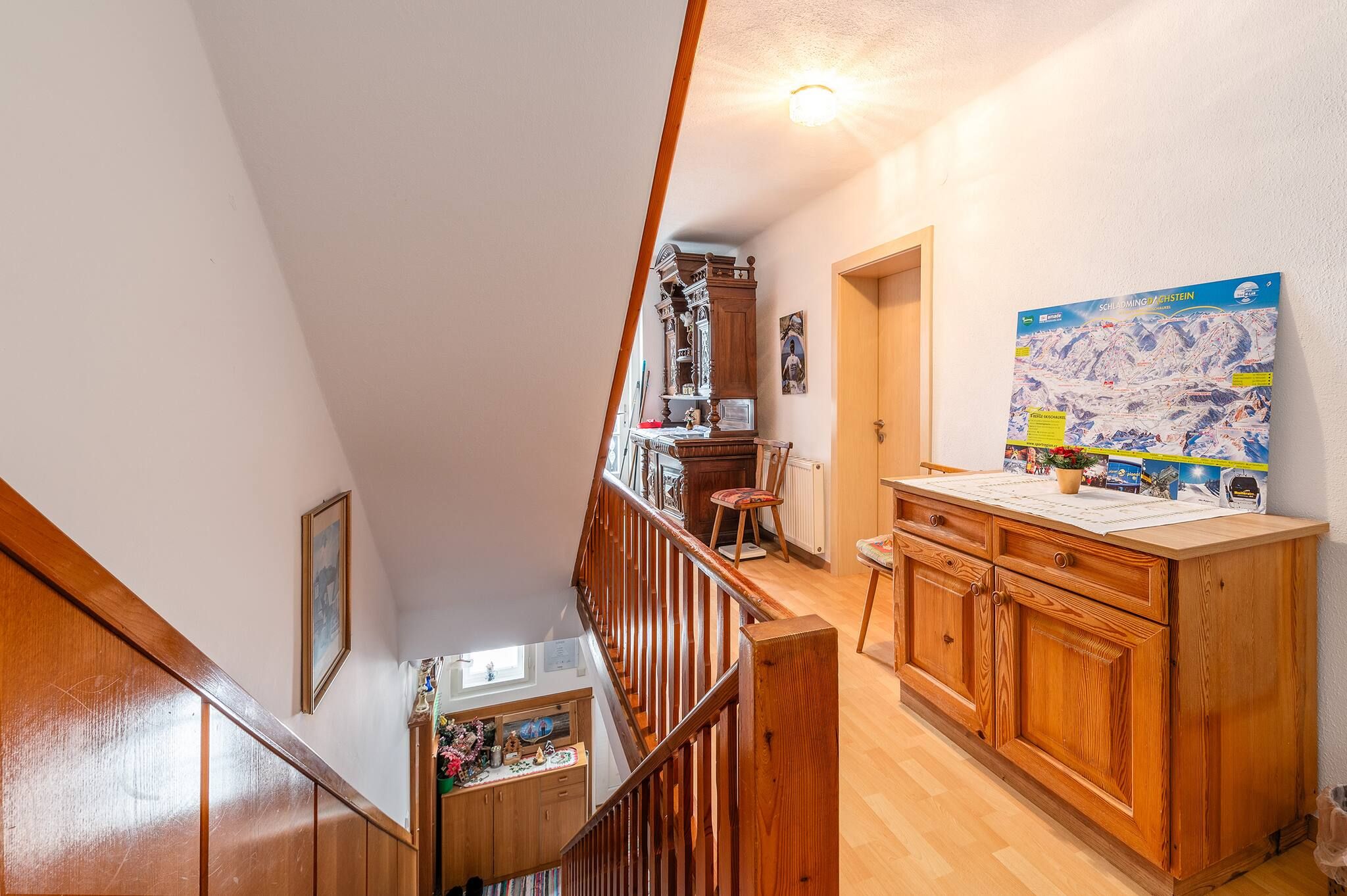 Una scala di legno conduce a una stanza con un armadietto di legno e una mappa appesa al muro.