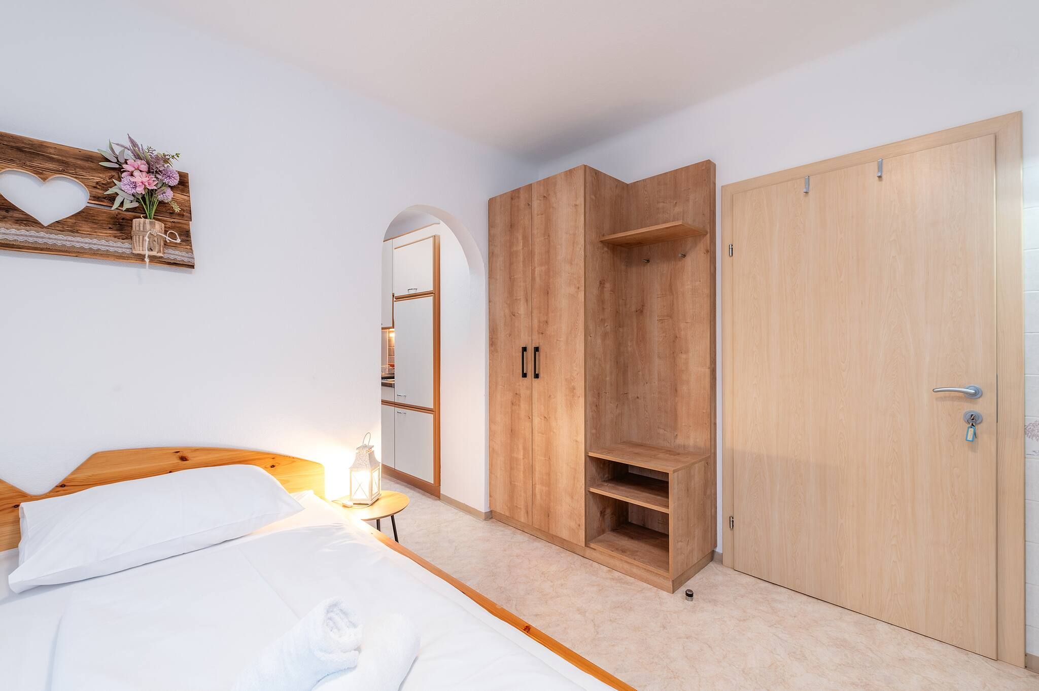 Una camera da letto con un letto, un armadio e un comodino con una lampada.